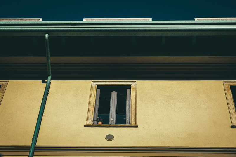 Gutter Cleaning — From below of aged dwelling building exterior with window on front wall in city in sunlight